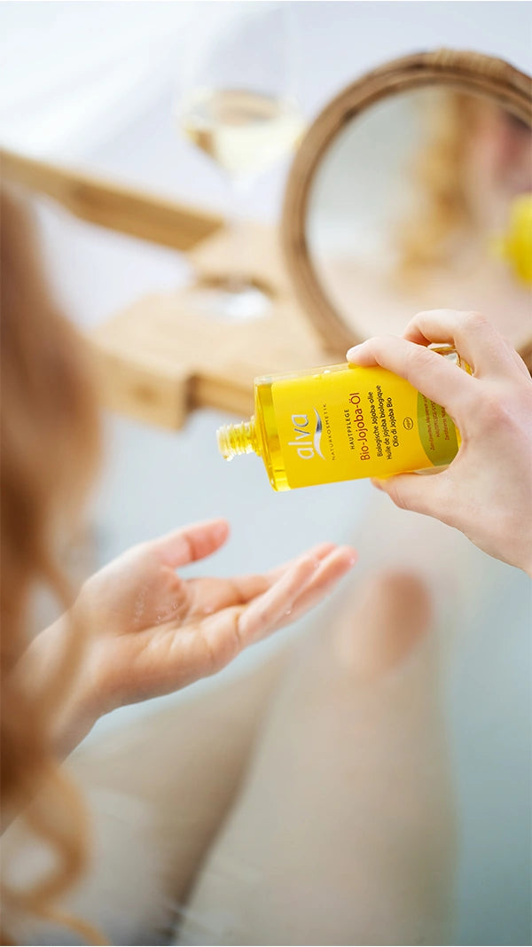 Das Bio Jojoba Öl von alva Naturkosmetik wird auf die Haut aufgetragen. Das Model ist nicht ganz zu sehen. Man erkennt, dass sie in der Badewanne ist.