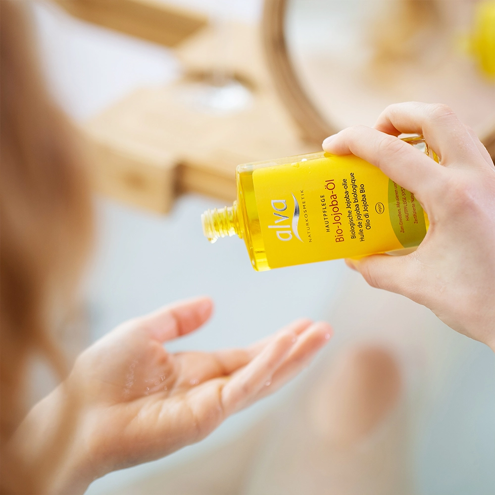 Hand mit alva Jojobaöl Bio, welches auf die Hand aufgetragen wird Hand mit alva Jojobaöl Bio, welches auf die Hand aufgetragen wird