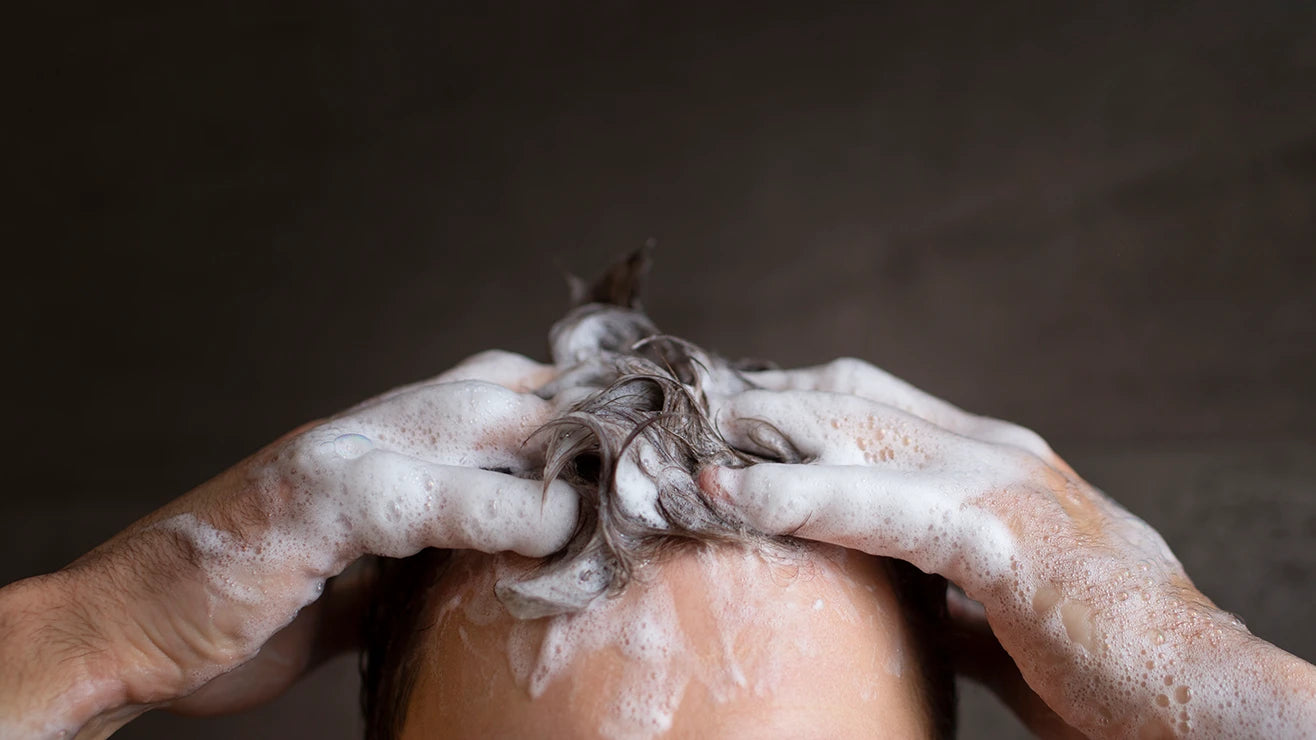 Mann wäscht sich die Haare mit dem Reactivate Koffein Shampoo von alva Naturkosmetik. Man sieht nur seine Stirn und die Haare, welche aufgeschäumt sind von dem Shampoo.
