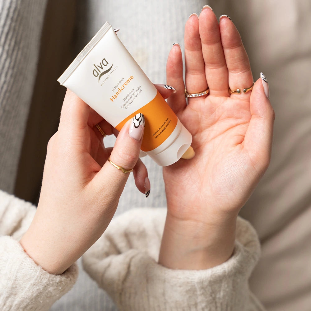 Model hält alva Handcreme Sanddorn in der Hand und trägt es auf die Hand Innenfläche auf.