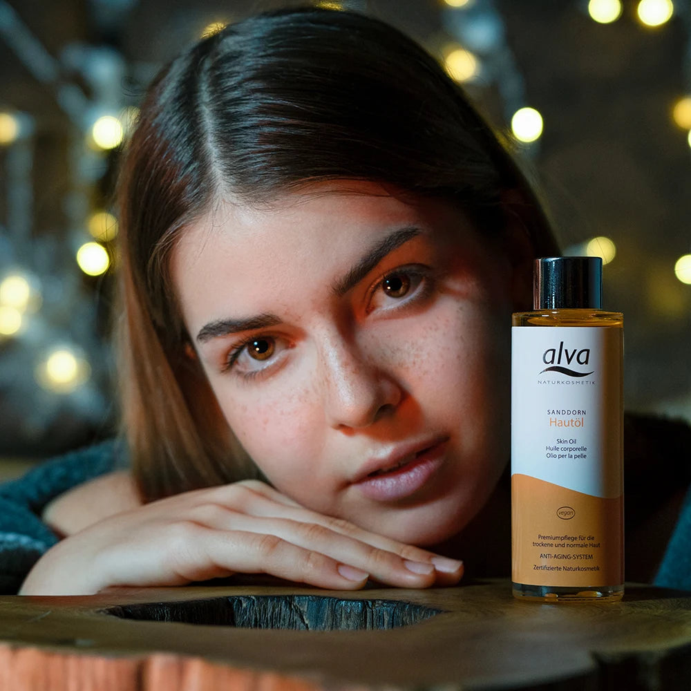 Model schaut in die Kamera und alva Hautöl Sanddorn steht neben ihr.
