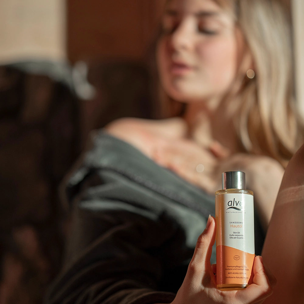 Model im Hintergrund unscharf und hält alva Hautöl Sanddorn in Hand, welches im Fokus ist.