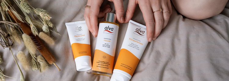 Es liegen drei alva Naturkosmetik Produkte auf einer Decke mit Trockenblumen links daneben. Es sind die Hände einer Frau zu sehen. Es liegt die Sanddorn Handcreme, das Sanddorn Hautöl sowie die Sanddorn Körperlotion aus. Das Bild ist in 1440x512 Pixeln. Es liegen drei alva Naturkosmetik Produkte auf einer Decke mit Trockenblumen links daneben. Es sind die Hände einer Frau zu sehen. Es liegt die Sanddorn Handcreme, das Sanddorn Hautöl sowie die Sanddorn Körperlotion aus. Das Bild ist in 1440x512 Pixeln.