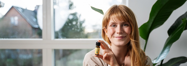 Das alva Naturkosmetik Model Paulina hat das Manukaöl sowie das Teebaumöl von alva Naturkosmetik in ihren Händen, sie schaut zufrieden in die Kamera, es ist ein Portrait, Desktop Banner.