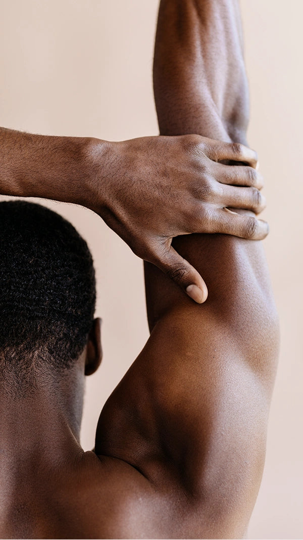 Farbiges, muskulöses, männliches Model hat den rechten Arm nach oben ausgestreckt.