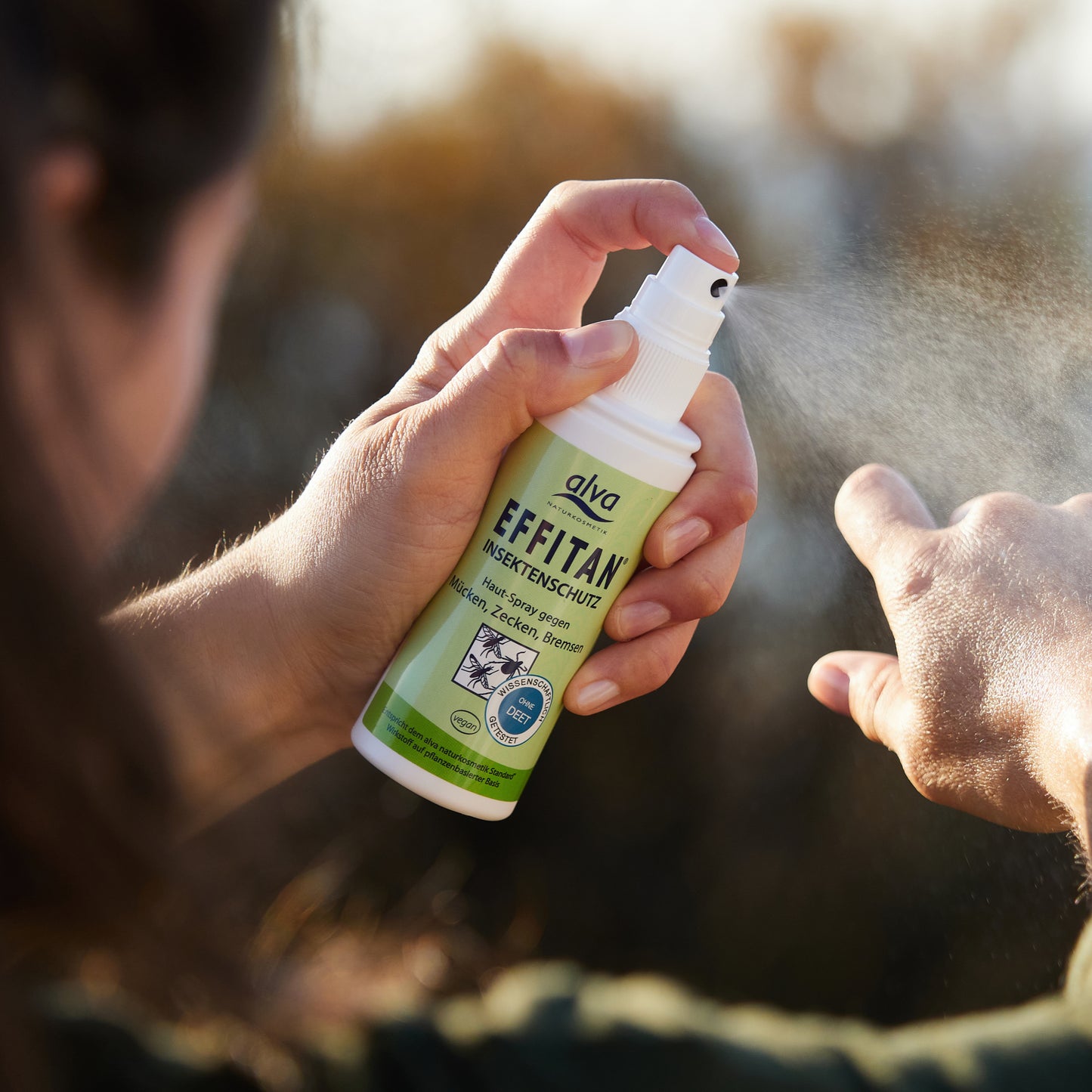 alva Effitan Spray sprüht das Insektenschutzmittel auf die Haut eines Models auf