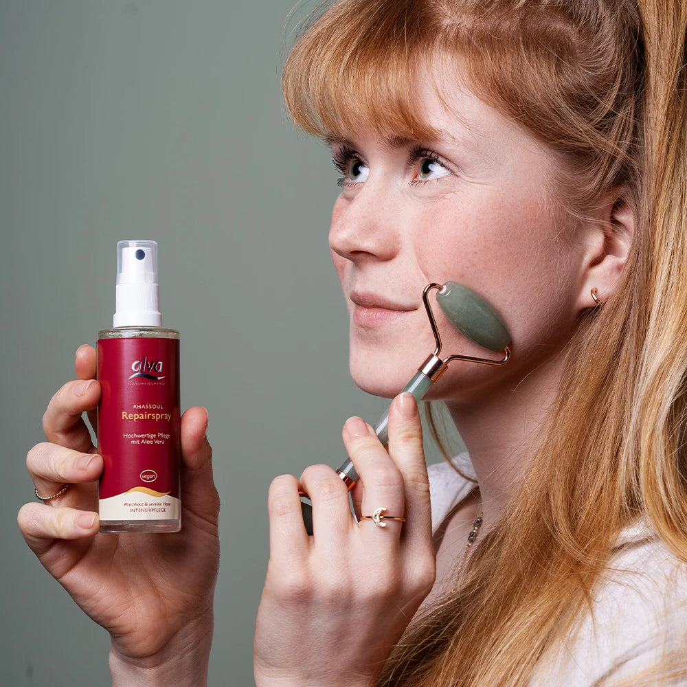 alva Naturkosmetik Model hält alva Rhassoul® Repairspray in Hand und trägt sich dieses ins Gesicht auf.