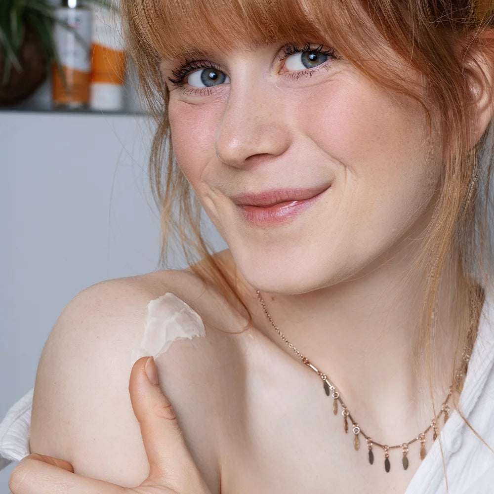 Model trägt alva Körperlotion Sanddorn auf Schulter auf und schaut glücklich in die Kamera