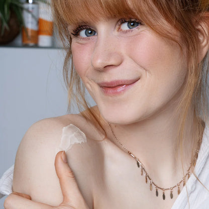 Model trägt alva Körperlotion Sanddorn auf Schulter auf und schaut glücklich in die Kamera